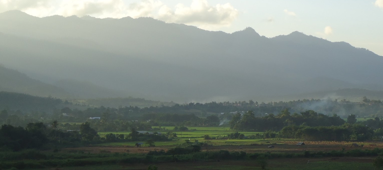 The Pai valley at golden hour, with fields and trees below layered mountains